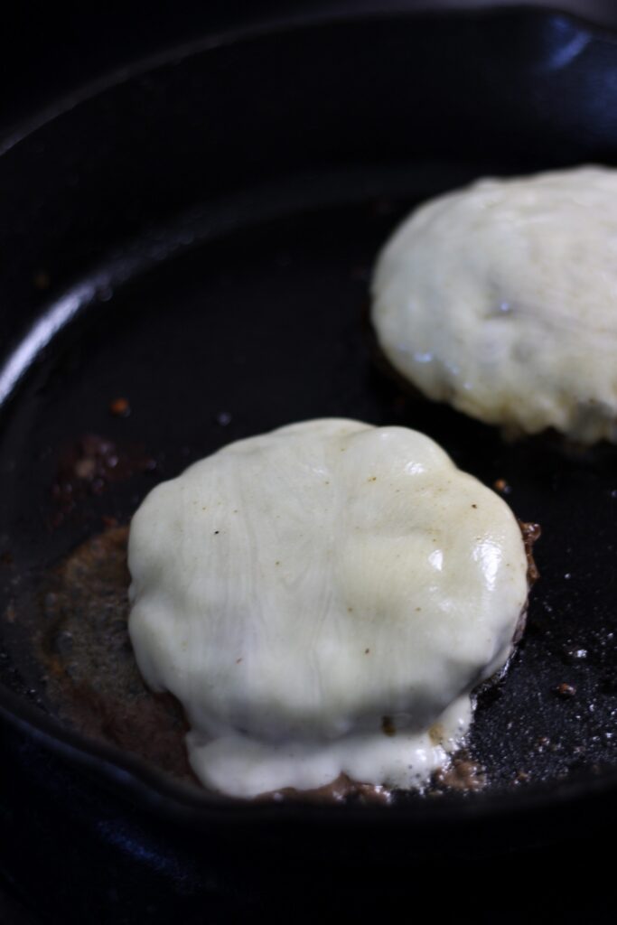 cooking a burger on a cast iron skillet